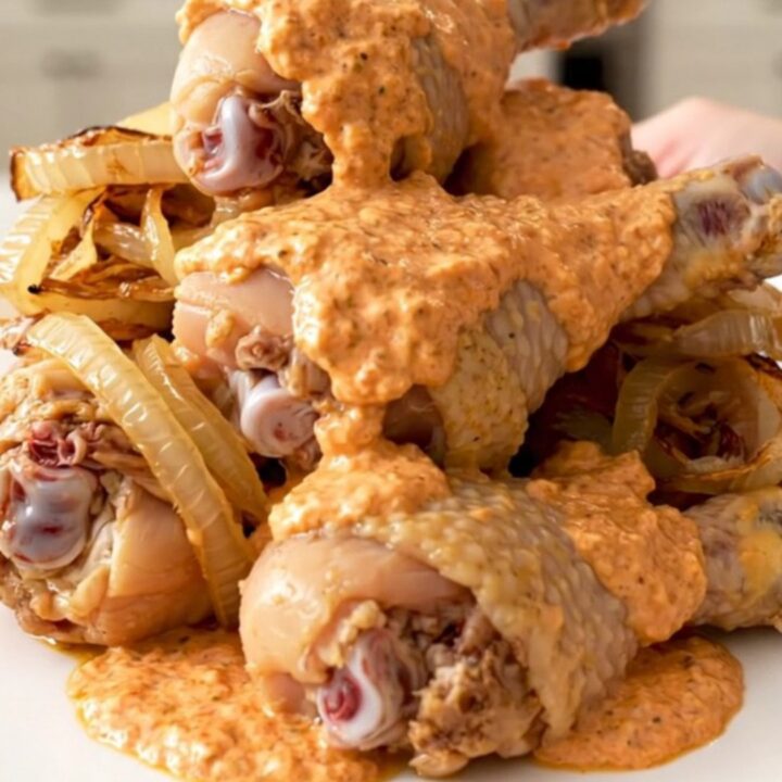 Slow cooker chicken drumsticks coated in a creamy, pink-orange comeback sauce on a white plate.