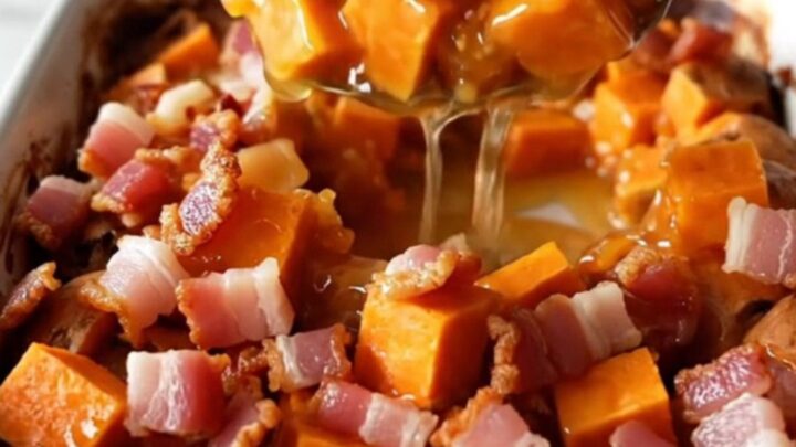 A golden, caramelized sweet potato bake in a white ceramic dish with crispy bacon pieces on top.