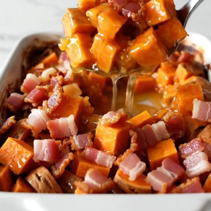 A golden, caramelized sweet potato bake in a white ceramic dish with crispy bacon pieces on top.