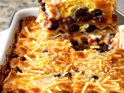 A top-down view of a golden, baked Huevos Rancheros casserole in a rectangular white dish.