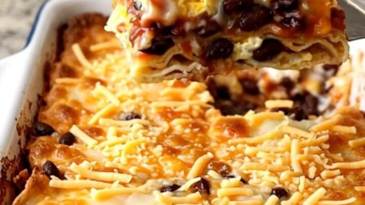 A top-down view of a golden, baked Huevos Rancheros casserole in a rectangular white dish.