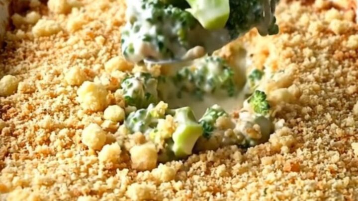 A golden, bubbling broccoli casserole in a white ceramic dish on a granite countertop.