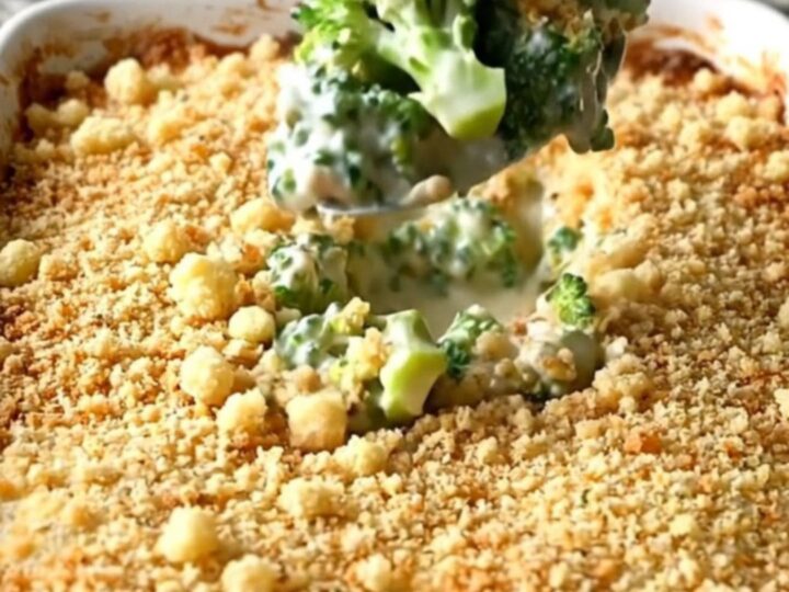 A golden, bubbling broccoli casserole in a white ceramic dish on a granite countertop.