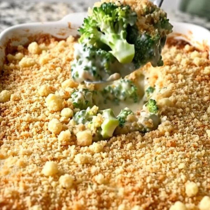 A golden, bubbling broccoli casserole in a white ceramic dish on a granite countertop.