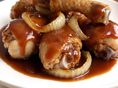 Close-up view of cooked cola-glazed chicken drumsticks arranged neatly on a white plate.