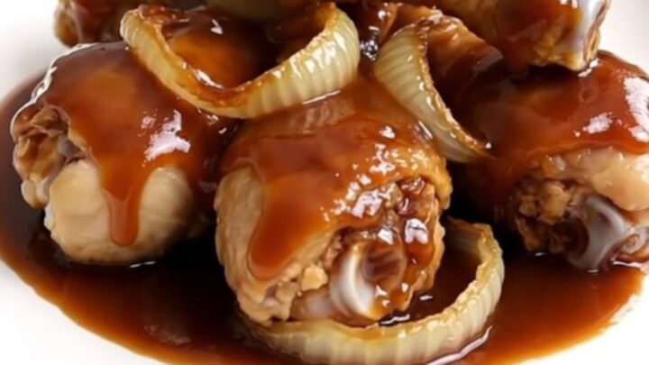 Close-up view of cooked cola-glazed chicken drumsticks arranged neatly on a white plate.