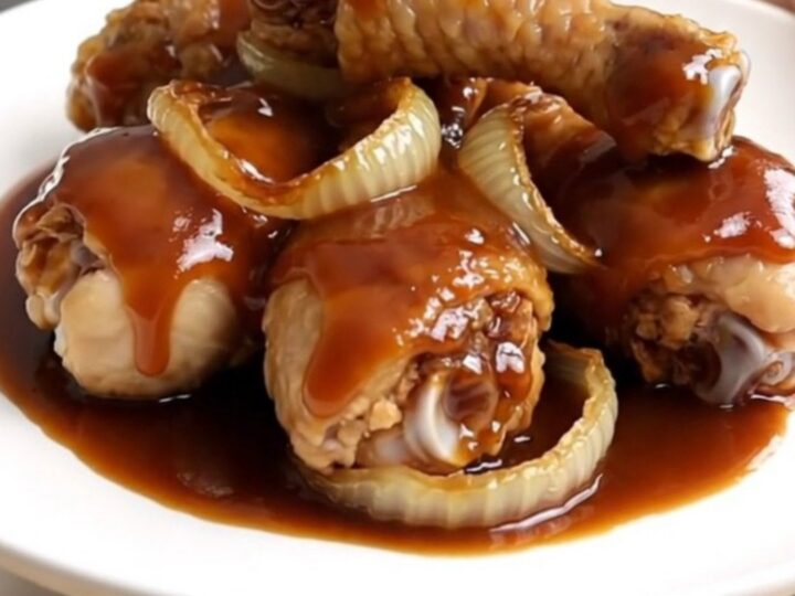 Close-up view of cooked cola-glazed chicken drumsticks arranged neatly on a white plate.
