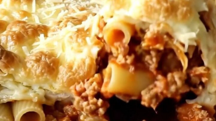 A golden, bubbly pastitsio bake in a rectangular ceramic dish, fresh from the oven.