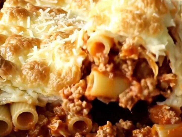 A golden, bubbly pastitsio bake in a rectangular ceramic dish, fresh from the oven.