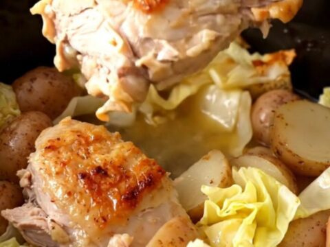 A slow cooker filled with cooked turkey tenderloins, cabbage wedges, and halved baby potatoes in a savory broth.