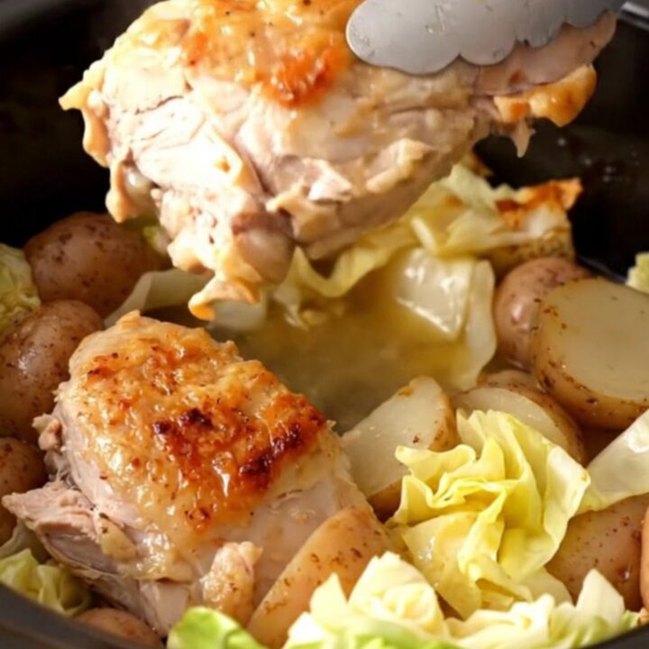 A slow cooker filled with cooked turkey tenderloins, cabbage wedges, and halved baby potatoes in a savory broth.