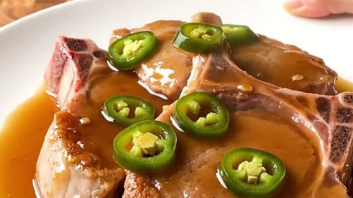 Slow cooker cowboy candy pork chops served on a white plate with a glossy sauce.
