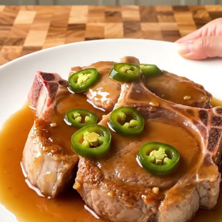 Slow cooker cowboy candy pork chops served on a white plate with a glossy sauce.