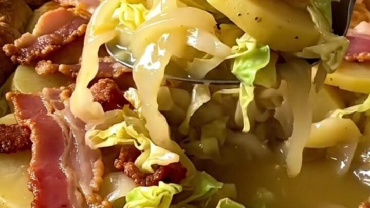 A rectangular ceramic dish filled with layers of tender cabbage, sliced gold potatoes, and crispy bacon.