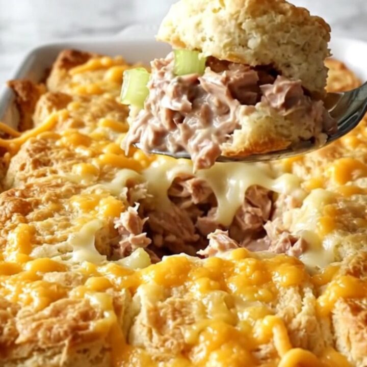 A golden, bubbling tuna melt biscuit bake in a white ceramic dish.