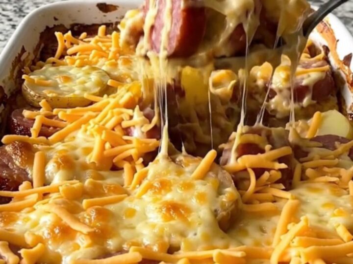A golden, bubbling pimento cheese and kielbasa potato casserole in a white ceramic dish.