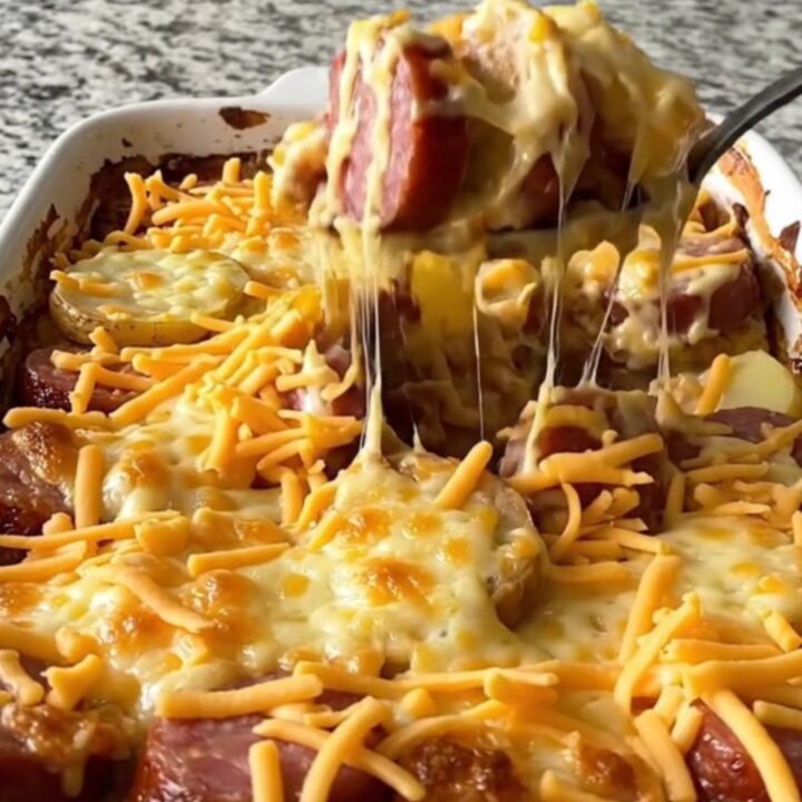 A golden, bubbling pimento cheese and kielbasa potato casserole in a white ceramic dish.