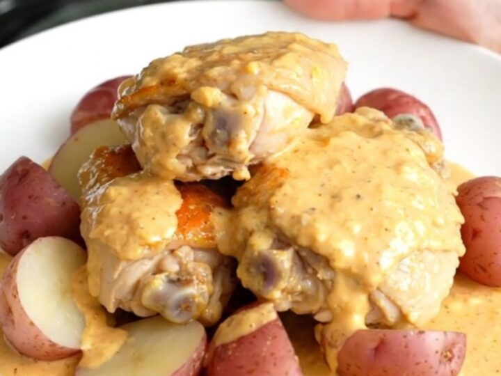 A close-up of creamy Chesapeake chicken thighs and baby red potatoes served on a white plate.