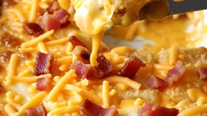 A top-down view of a rectangular ceramic dish filled with crispy potato tots covered in beer cheese, cheddar, and bacon.