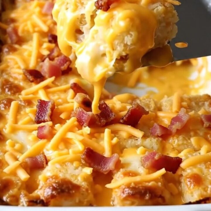 A top-down view of a rectangular ceramic dish filled with crispy potato tots covered in beer cheese, cheddar, and bacon.
