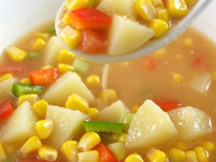 A top-down view of a creamy Cajun corn chowder in a slow cooker insert on a granite countertop.