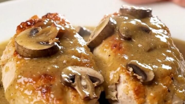 A top-down view of creamy bourbon mushroom chicken served on a white plate with visible steam.