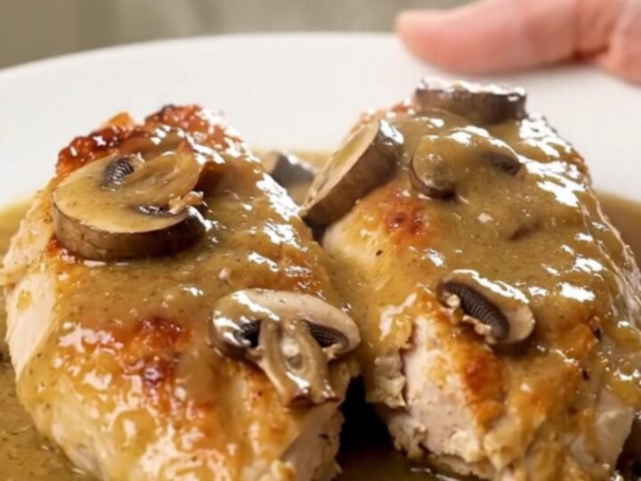 A top-down view of creamy bourbon mushroom chicken served on a white plate with visible steam.