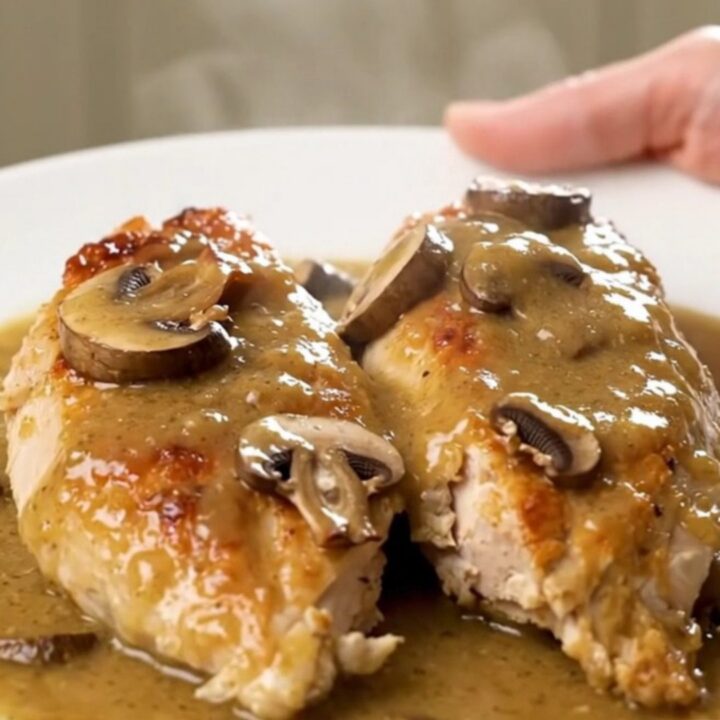 A top-down view of creamy bourbon mushroom chicken served on a white plate with visible steam.