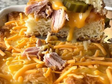 A top-down view of a golden, bubbling dill pickle turkey cheeseburger bake in a white rectangular dish.