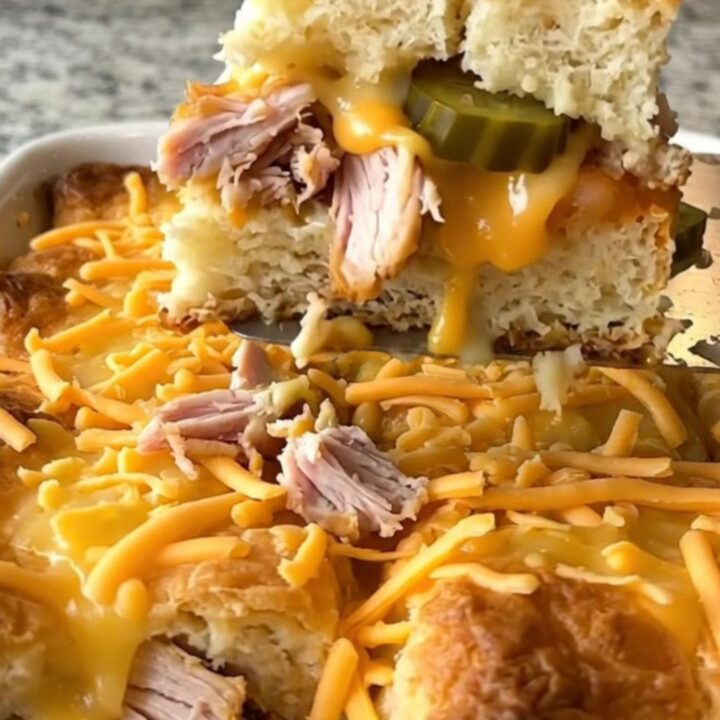 A top-down view of a golden, bubbling dill pickle turkey cheeseburger bake in a white rectangular dish.