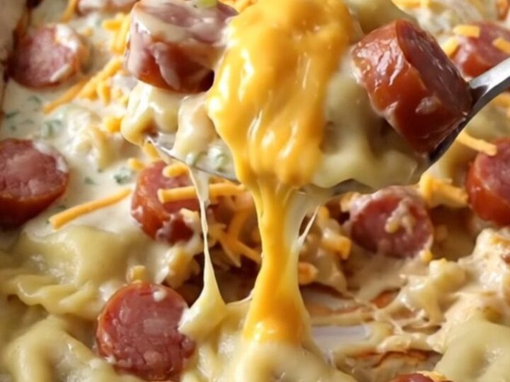 A top-down view of a ceramic baking dish filled with potato pierogi, kielbasa coins