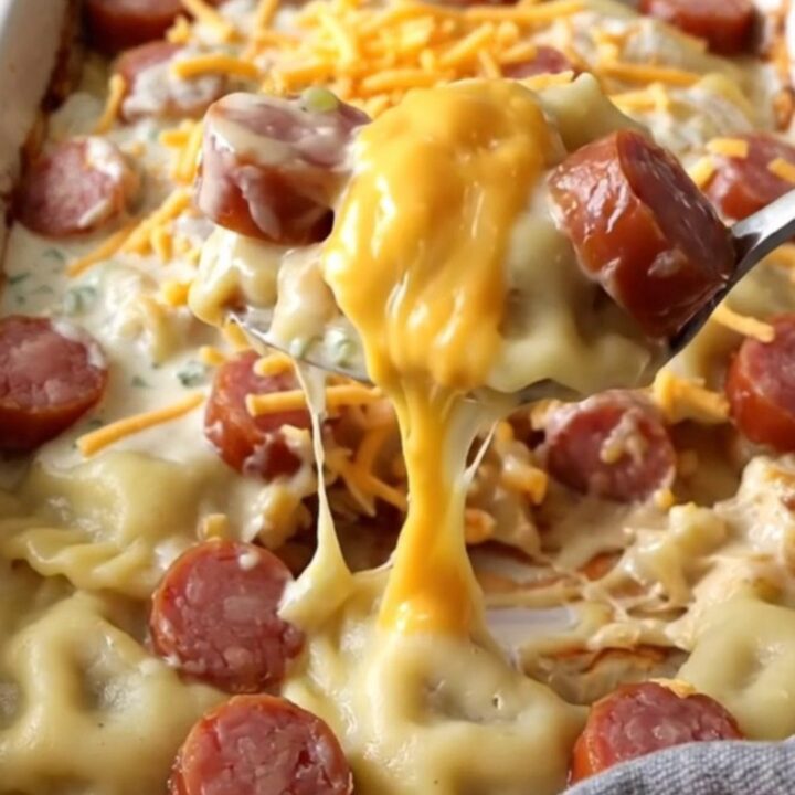 A top-down view of a ceramic baking dish filled with potato pierogi, kielbasa coins