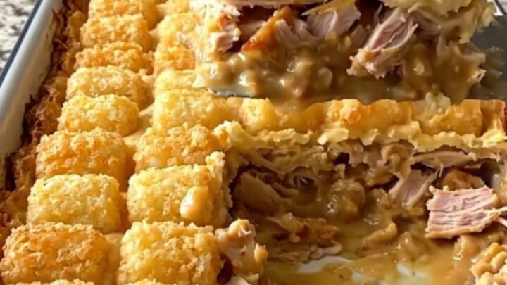 A golden, bubbling French onion turkey potato tot casserole in a white baking dish.