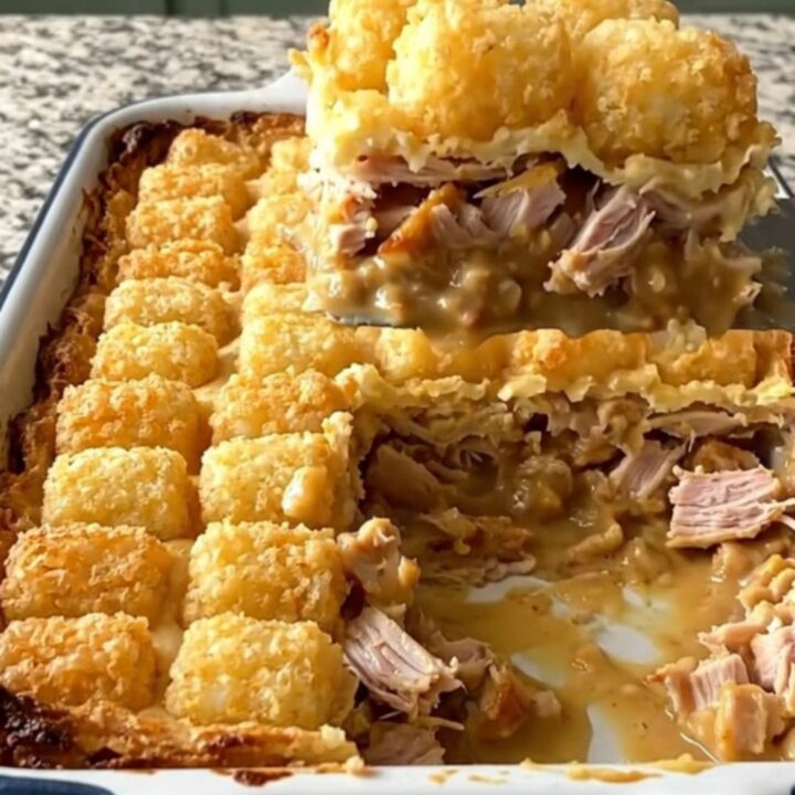 A golden, bubbling French onion turkey potato tot casserole in a white baking dish.