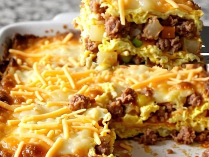 A golden, bubbling Cowboy Breakfast Casserole in a white ceramic dish on a light granite counter.