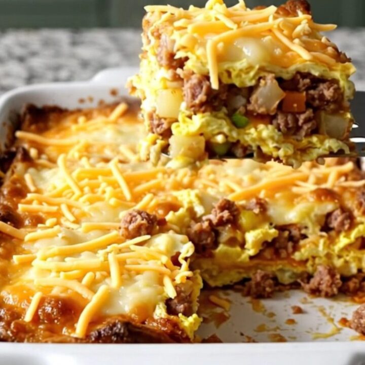 A golden, bubbling Cowboy Breakfast Casserole in a white ceramic dish on a light granite counter.