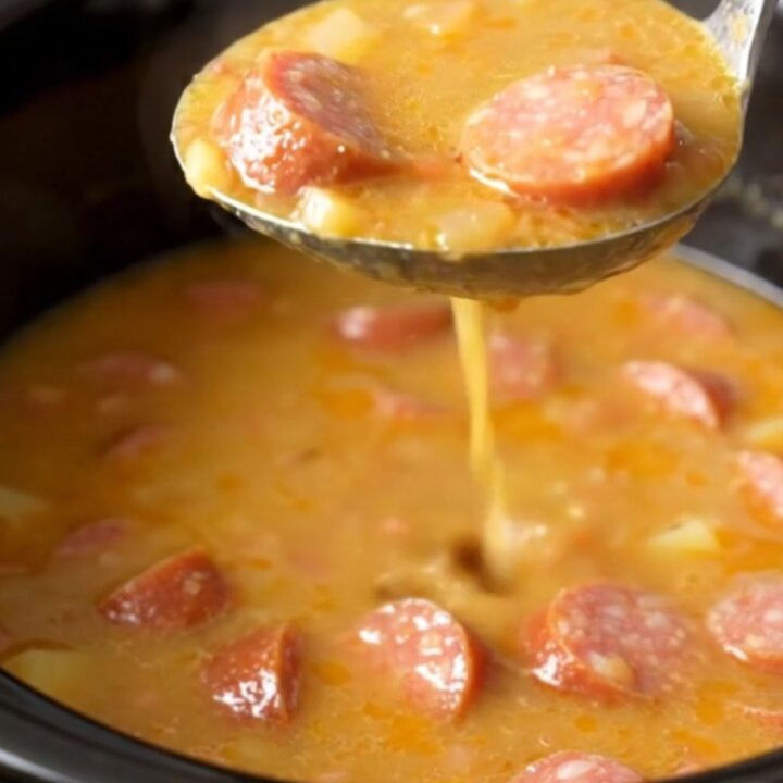 A close-up of a bowl filled with creamy sausage and potato soup with visible sausage coins and sun-dried tomatoes.