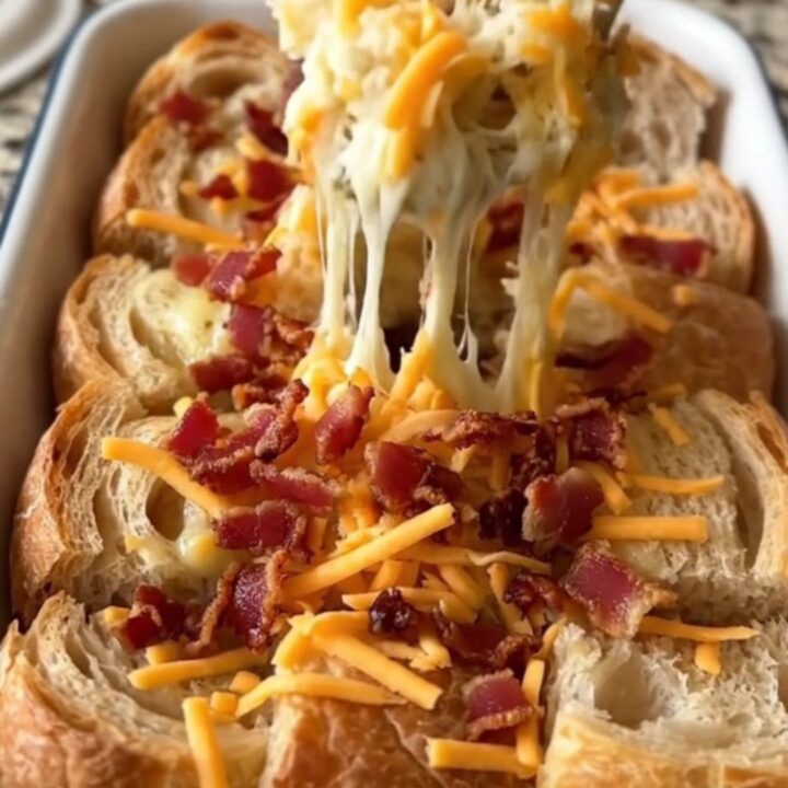A large rectangular baker filled with golden-brown pull-apart bread topped with melted cheddar and crispy bacon.