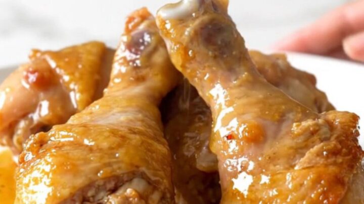 Slow cooker honey lemon pepper chicken drumsticks with a glossy glaze on a white plate.