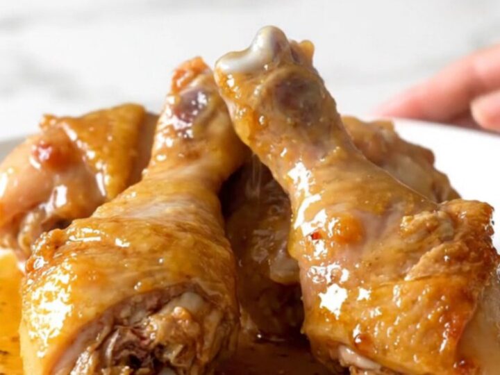 Slow cooker honey lemon pepper chicken drumsticks with a glossy glaze on a white plate.