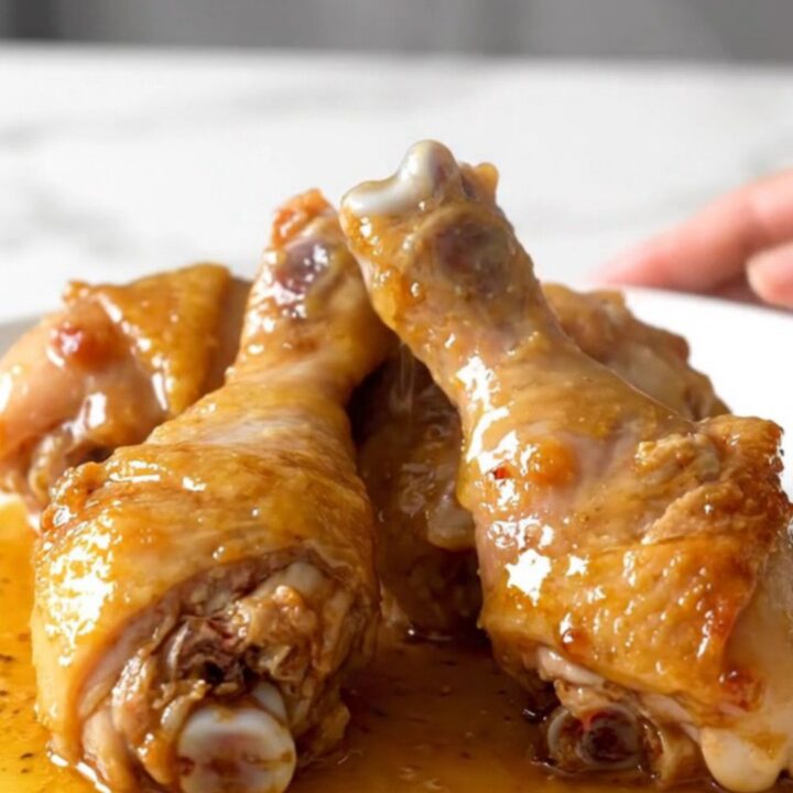 Slow cooker honey lemon pepper chicken drumsticks with a glossy glaze on a white plate.