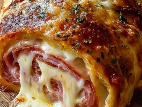 A close-up shot of a golden-brown chicken cordon bleu stromboli sliced on a wooden board
