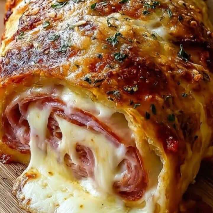 A close-up shot of a golden-brown chicken cordon bleu stromboli sliced on a wooden board