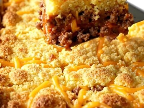 A golden-brown sloppy joe cornbread casserole in a white ceramic dish.