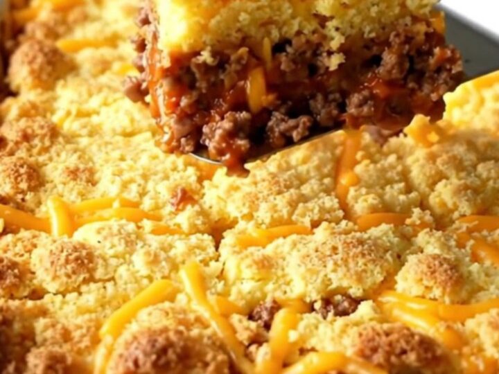A golden-brown sloppy joe cornbread casserole in a white ceramic dish.