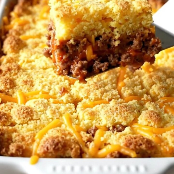 A golden-brown sloppy joe cornbread casserole in a white ceramic dish.
