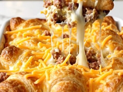 A golden, bubbly sausage and cream cheese crescent bake in a white ceramic dish.