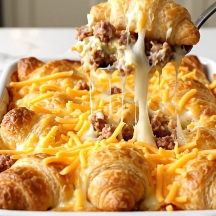 A golden, bubbly sausage and cream cheese crescent bake in a white ceramic dish.