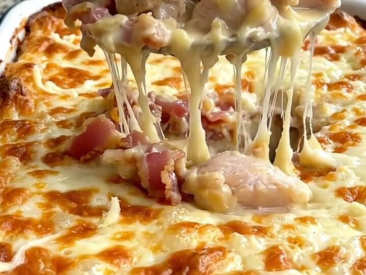 A large rectangular baking dish filled with creamy chicken and penne pasta, topped with melted mozzarella and crispy bacon.