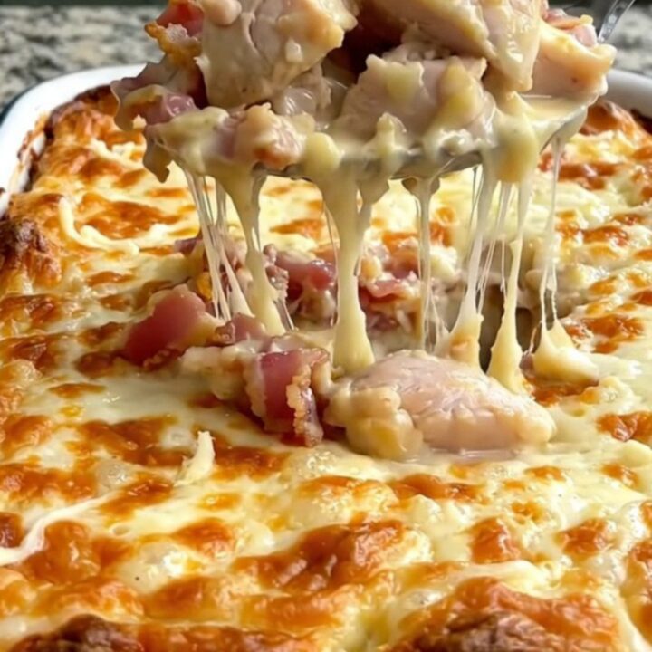 A large rectangular baking dish filled with creamy chicken and penne pasta, topped with melted mozzarella and crispy bacon.